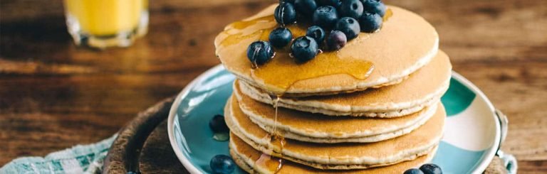 Uova a colazione sotto forma di pancake con sciroppo e mirtilli